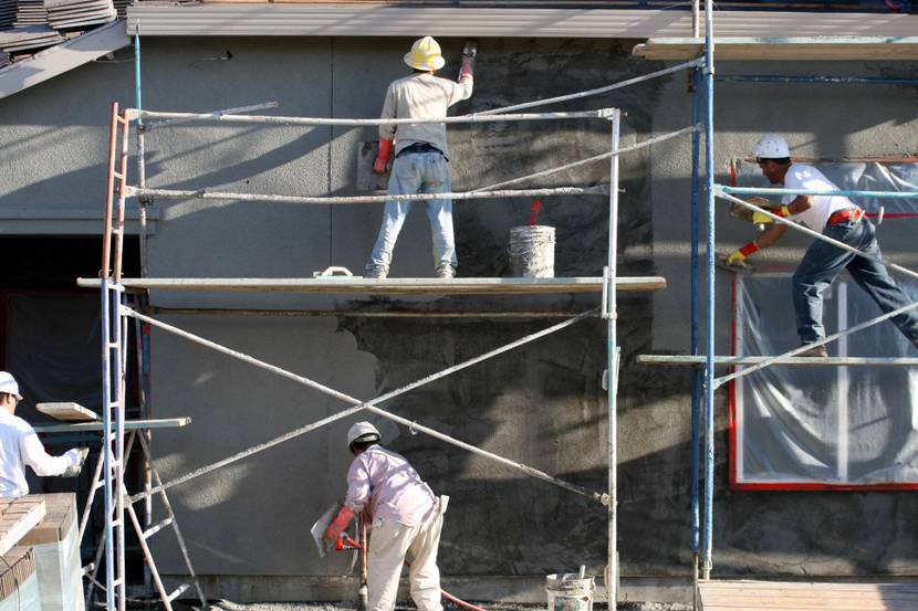 Handwerker stehen auf einem Gerüst.