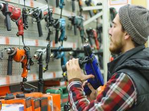 mann prueft werkzeug im baumarkt