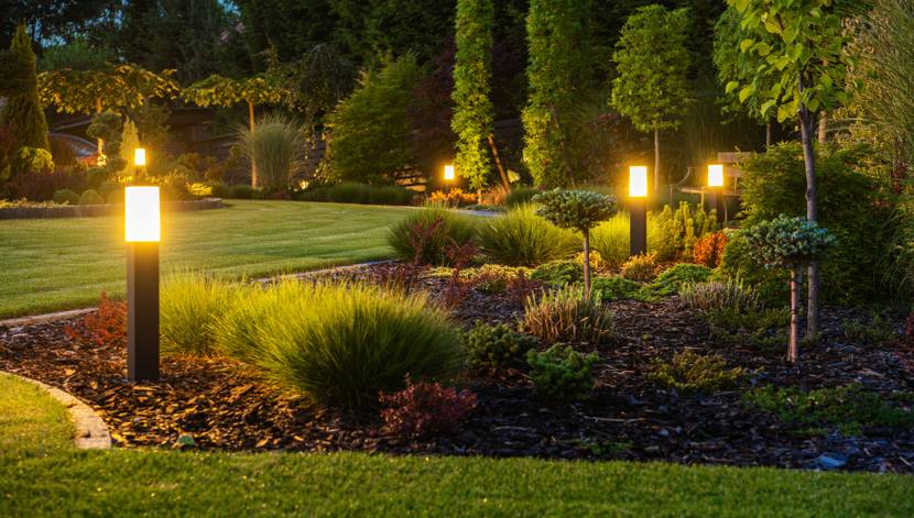 In einem Garten leuchten LED-Lampen die Beete aus.