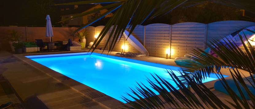 Beleuchteter Gartenpool bei Nacht.