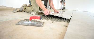 Handwerker arbeiten in einem Neubau, verlegen Fliesen