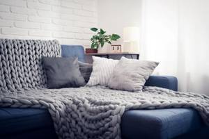 couch mit grauen dekokissen und decke
