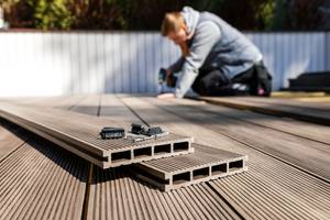 Mann baut eine Terrasse aus Holz.