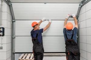 zwei Männer bauen ein Garagentor ein