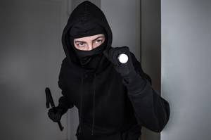 Maskierter Einbrecher dringt mit Taschenlampe und Brecheisen in Wohnung ein