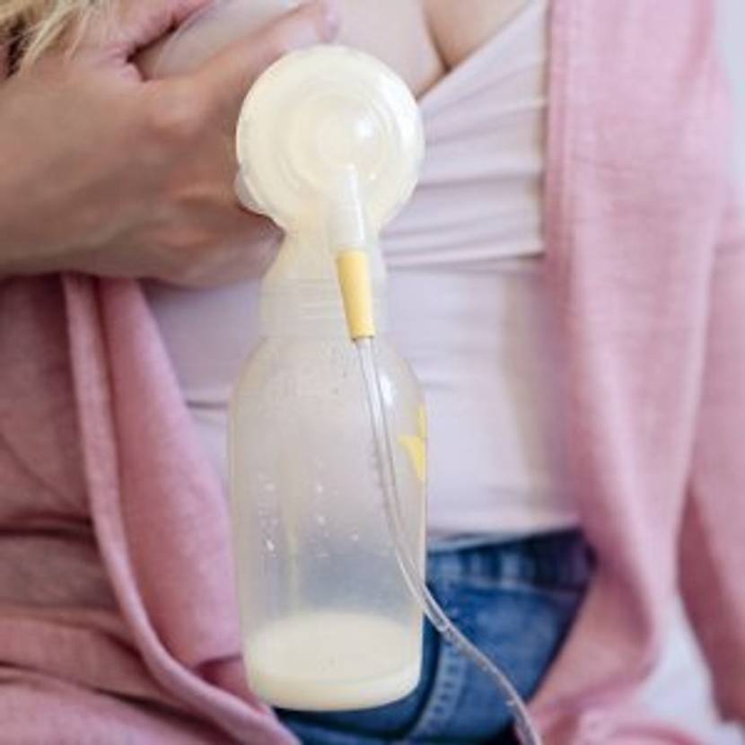 Frau hält elektrische Milchpumpe an die Brust
