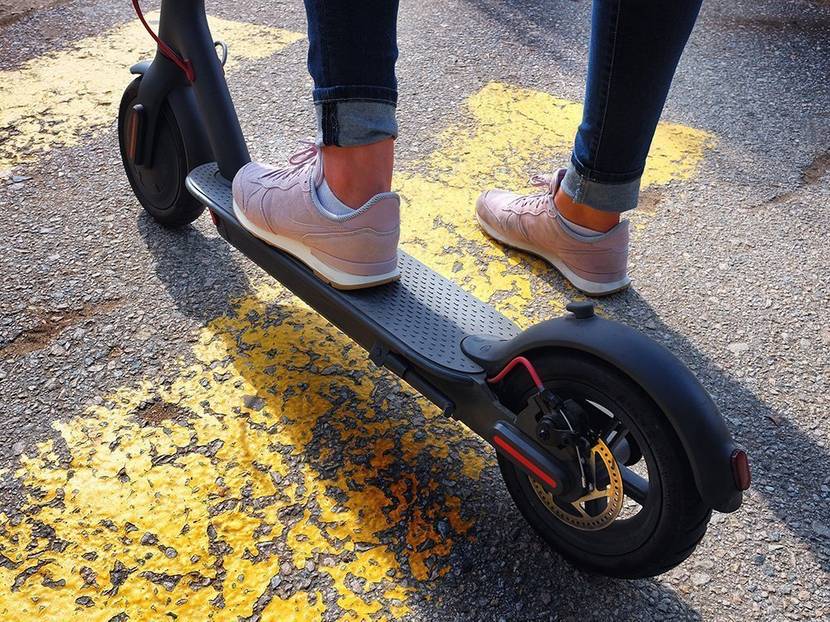 Mensch steht mit einem Bein auf Elektro-Scooter