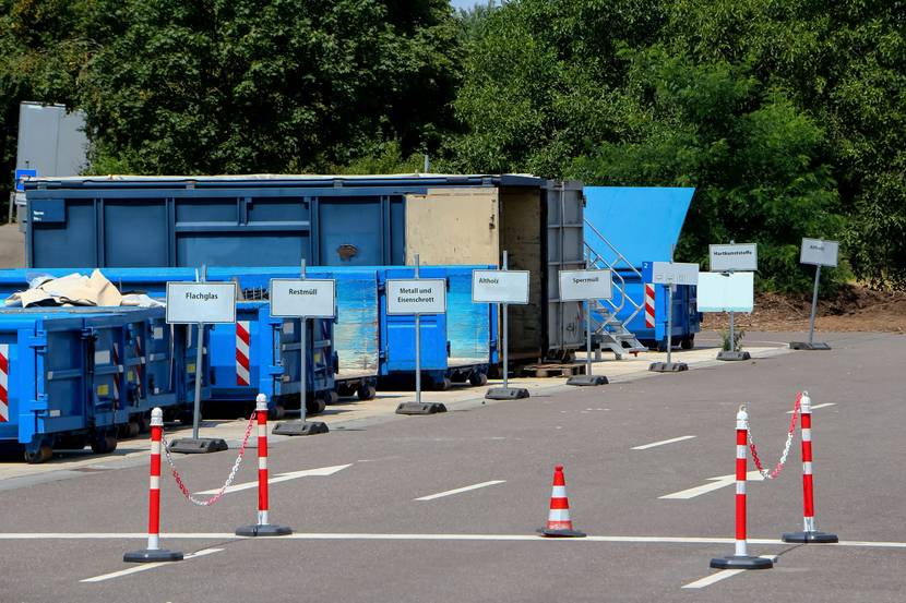 Auf einem gut sortierten Wertstoffhof stehen vor Müllcontainern Schilder mit dem entsprechenden Abfall.
