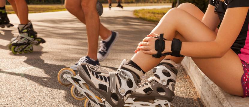 Inline-Skates für Damen getestet: Frau mit Inline-Skates und Handprotektoren sitzt auf einer Mauer.