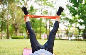Mann macht Sport im Garten mit Fitnessband