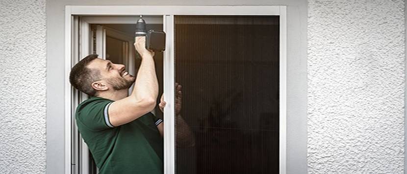freundlicher Handwerker montiert Insektenschutzgitter