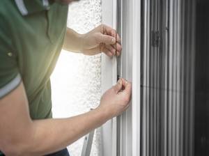 freundlicher Handwerker montiert Insektenschutzgitter
