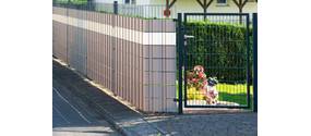 Doppelstabmattenzaun am Rand eines Gartens eines Hauses, davor Bürgersteig.