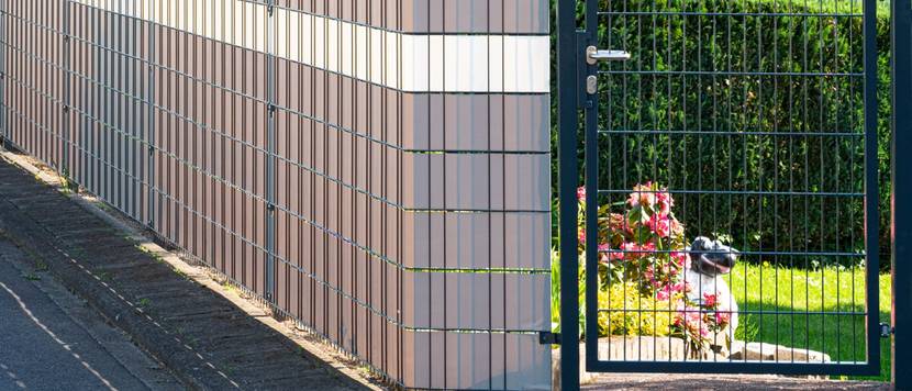 Doppelstabmattenzaun am Rand eines Gartens eines Hauses, davor Bürgersteig.