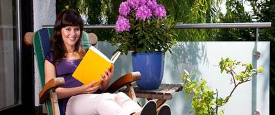 Junge Frau liest ein Buch im Garten