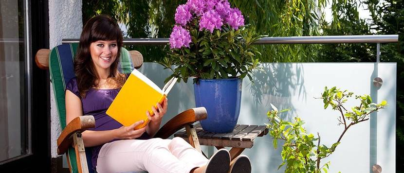 Junge Frau liest ein Buch im Garten