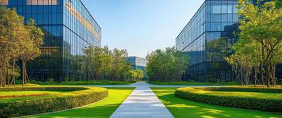 Ein Bürogelände mit einem Weg, gepflegten Grünanalgen unter einem blauen Himmel.