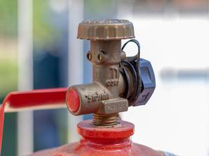 Metallventil einer Gasflasche an einem Gasgrill im Garten