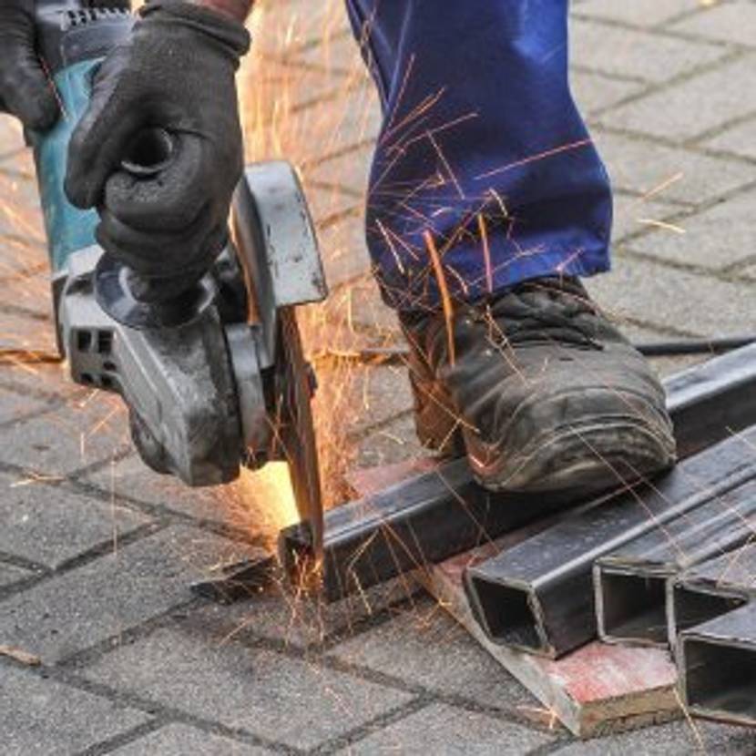 Bauarbeiter bearbeitet Eisen mit Winkelschleifer.