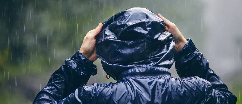 Herren-Regenjacke im Test: Starker Regen prasselt auf einen Mann in Regenjacke hinab.