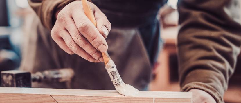 mann streicht holzleim auf