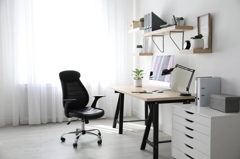 Ein helles Homeoffice mit einem ergonomischen Schreibtischstuhl vor einem Schreibtisch.