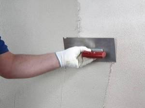Mit schräggestellter Glättkelle wird der Reibeputz von unten nach oben auf die Wand gezogen. Anschließend zieht man ihn scharf übers Korn ab.