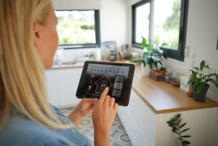 Eine Frau hält ein Tablet in der Hand und nutzt ein Smart-Home-Programm