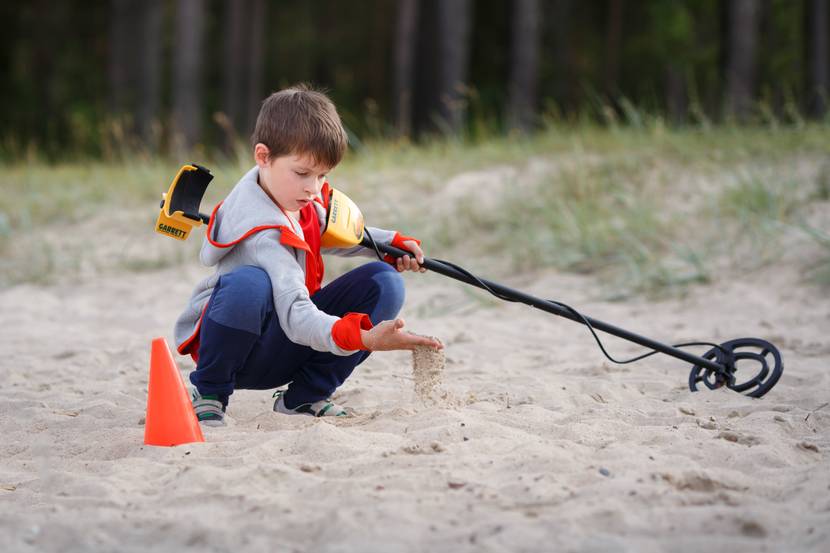 junge mit metalldetektor am strand