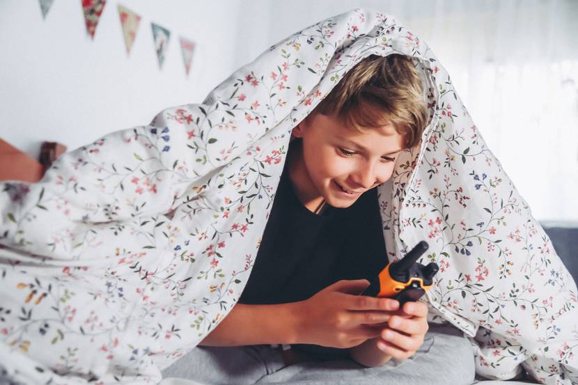 Junge spielt im Bett im Walkie-Talkie