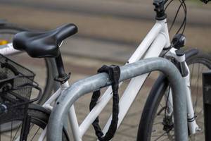 Fahrrad ist mit einem Kettenschloss an einem Fahrradständer gesichert.