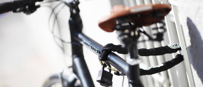 Fahrrad ist mit Kettenschloss an einem Gitter gesichert.