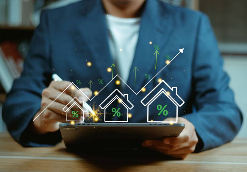 Ein Mann hält ein Tablet in der Hand. Im Vordergrund sind Symbole zu Häusern eingeblendet.