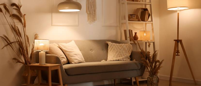 Ein modern eingerichtetes Wohnzimmer im Boho-Style wird durch mehrere Lampen beleuchtet.