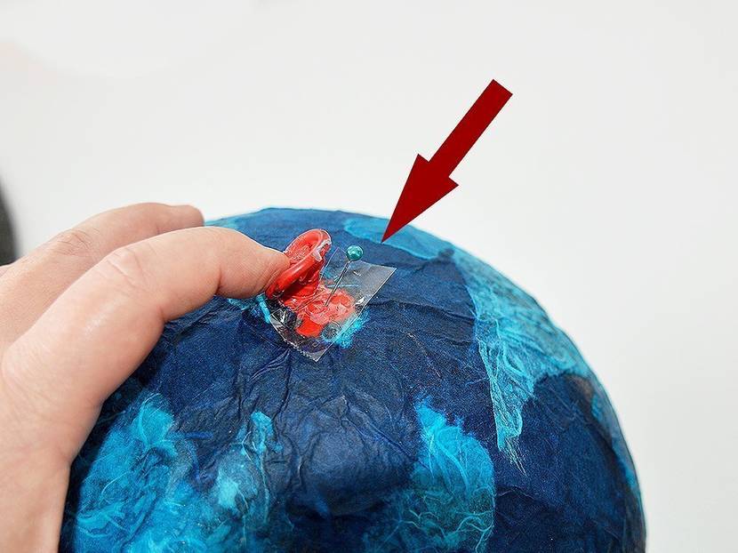 Durch den Klebefilm mit der Nadel einstechen, damit der Ballon nicht platzt.