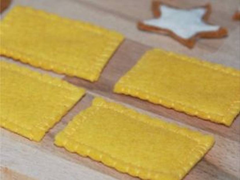 Aus Filz-Rechtecken und gelbem Garn können Sie leicht Butterkekse basteln.