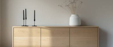 Sonnenlicht fällt auf einen Teil einer Wohnzimmer-Wand mit Sideboard.