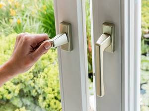 Eine Frau öffnet ein Fenster zum Lüften der Wohnung. Frische Luft im Zimmer
