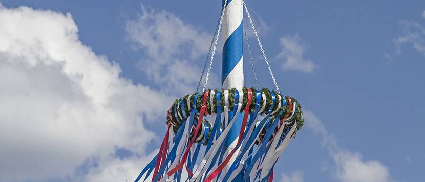 Bayrischer Maibaum vor weissblauem Wolkenhimmel