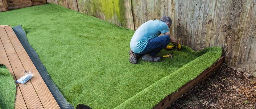 mann verlegt kunstrasen im garten