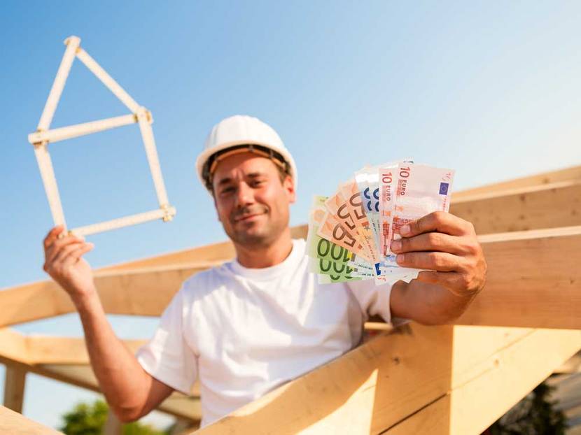 Bauarbeiter hält Geld hoch