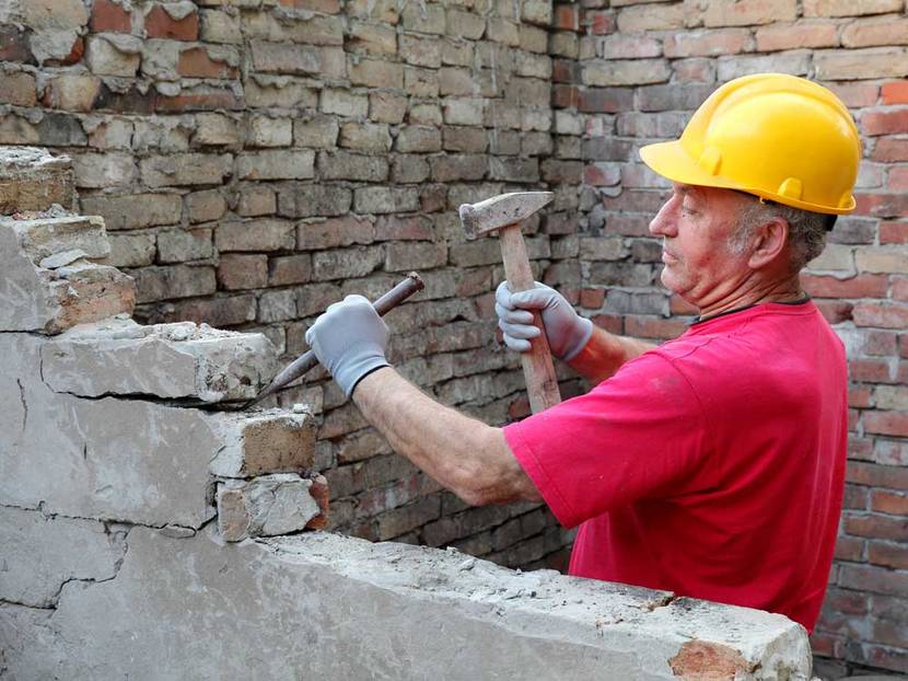 Älterer Bauarbeiter entfernt Mauersteine