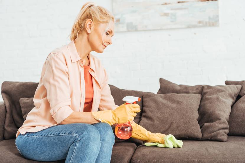 frau behandelt sofa mit milbenspray