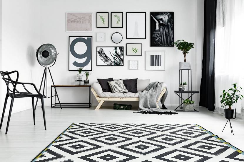 Ein schwarz-weiß eingerichtetes, minimalistisches Wohnzimmer mit einer präsenten Bildergalerie über dem Sofa.