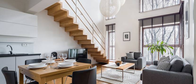 Offener Wohn- und Essbereich, der mit Holz und modernen, grauen Möbeln eingerichtet ist.