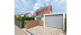 Modernes Wohnhaus mit Garage und sichtbarer Mülltonnen-Abdeckung.