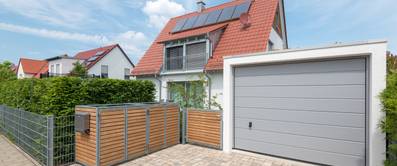 Modernes Wohnhaus mit Garage und sichtbarer Mülltonnen-Abdeckung.