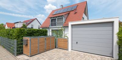 Modernes Wohnhaus mit Garage und sichtbarer Mülltonnen-Abdeckung.