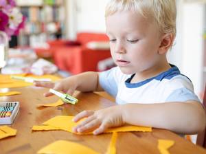 Kind bastelt mit Papier und Schere