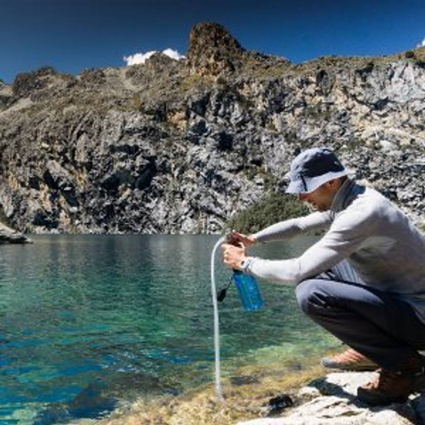 Wanderer filtert Wasser aus einem See.